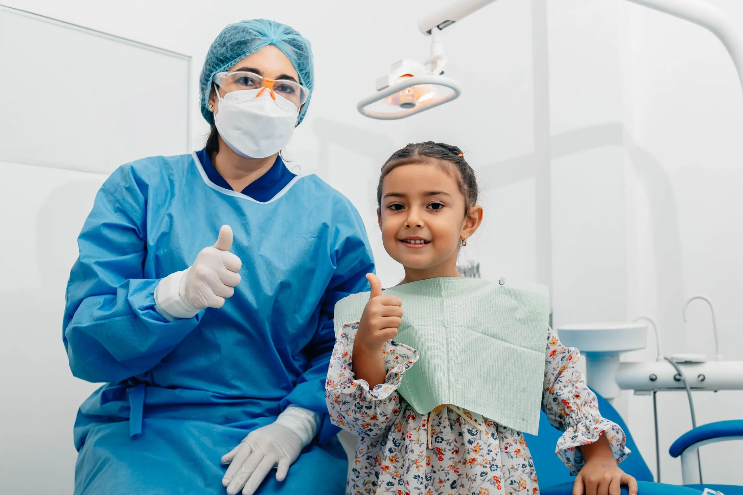 A young girl giving a thumbs up from the dental chair after her checkup