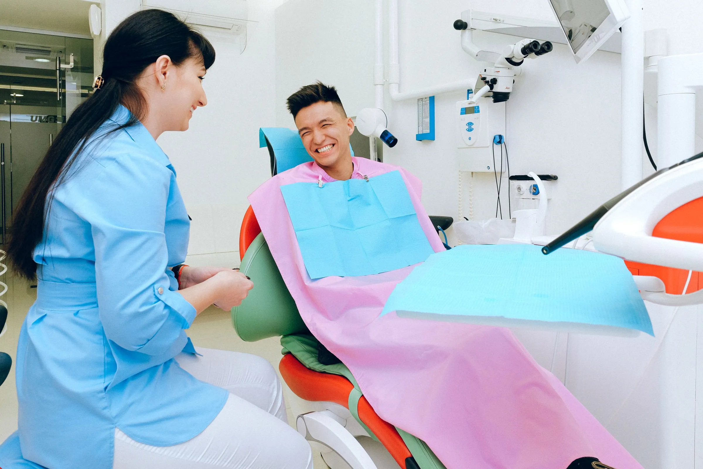 A patient laughing with a dental team member while sitting back in a bright treatment chair
